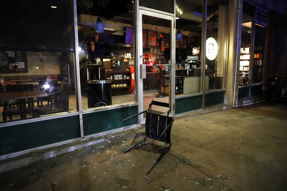 A chair is seen at the bottom of a broken window after police tried to clear a violent crowd Saturday, Sept. 16, 2017, in University City, Mo. Earlier, protesters marched peacefully in response to a n ...