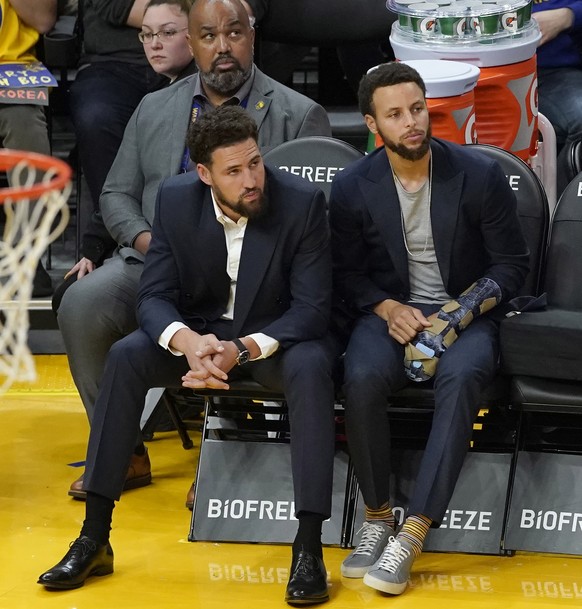epa08030173 Golden State Warriors guards Klay Thompson (L) and Stephen Curry (R) watch from the bench during the second half of their NBA game against Chicago Bulls at Chase Center in San Francisco, C ...