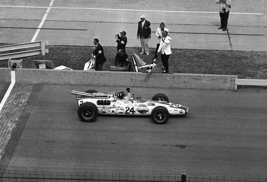 FILE - In this May 30, 1966, file photo, Graham Hill, driving a Lola- Ford, raises his arm in victory as he takes the checkered flag to win the 50th running of the Indianapolis 500 auto race at Indian ...