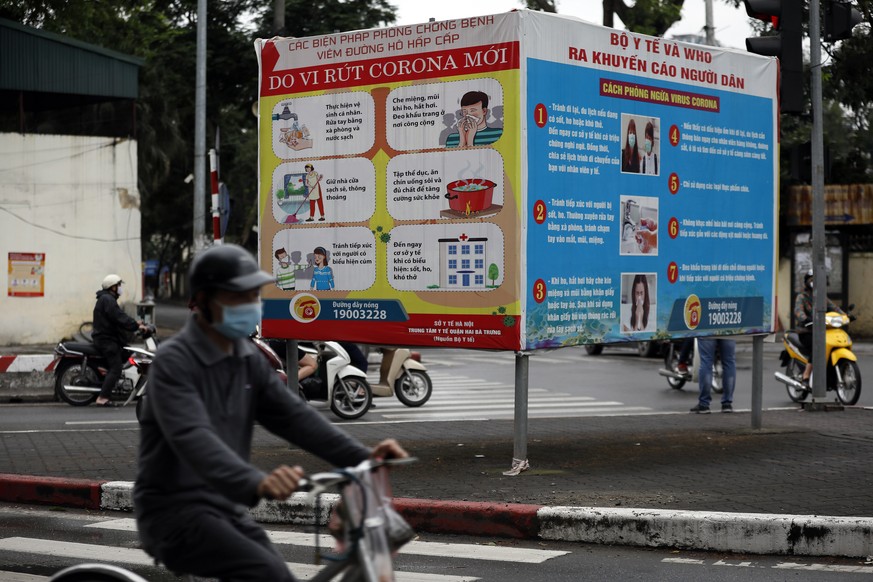 epa08381004 A man rides a bike past sign about the Covid-19 coronavirus in Hanoi, Vietnam 23 April 2020 (issued 24 April 2020). Communist propaganda, which was most visible during the Vietnam War, has ...