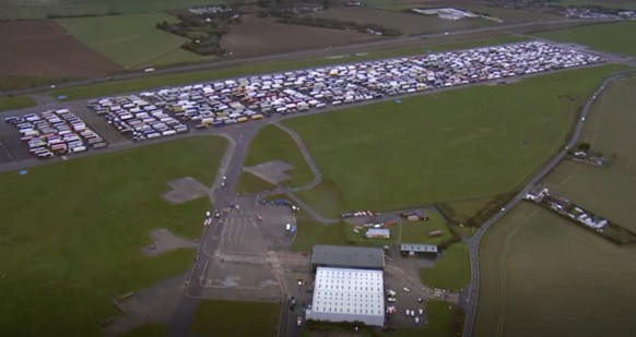 Trucks are parked in a holding area, in this aerial photo taken from video, lined up at former airfield in Manston, England, close to the M20 highway that runs to the port of Dover, Britain&#039;s mai ...