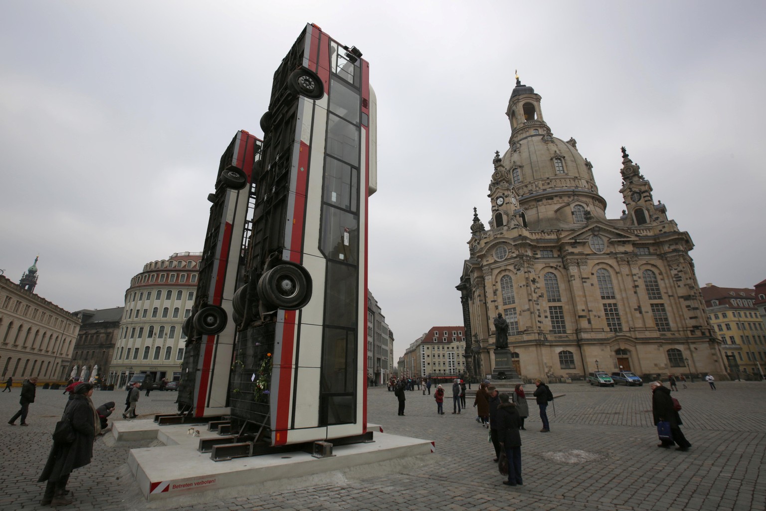 People walk next to the art instalation &quot;Monument&quot; by Syrian artist Manaf Halbouni, made from three passenger busses in Dresden, Germany February 8, 2017. REUTERS/Matthias Schumann