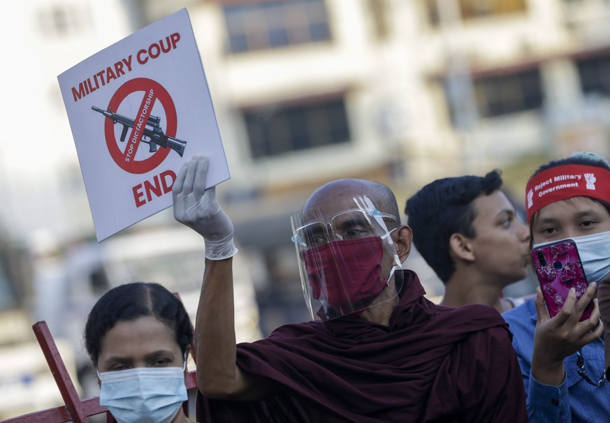 epa09012305 A Myanmar Buddhist monk holds a placard as he takes part a protest against the military coup in Yangon, Myanmar, 14 February 2021. Protests against the military coup continued across the c ...