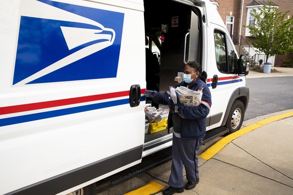 epa08389786 A mail carrier of the United States Postal Service (USPS) wearing a protective face mask delivers mail to residences in Silver Spring, Maryland, USA, 28 April 2020. US President Donald J.  ...