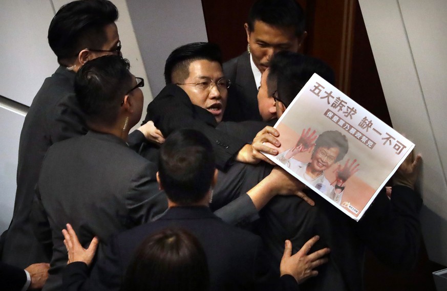 Pro-democracy lawmaker Gary Fan, center, is forcibly removed by security officials as he protests while Hong Kong Chief Executive Carrie Lam delivers her speech at a question and answer session at the ...