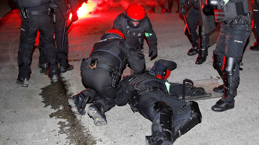 epa06555413 A member of the Ertzaintza (Basque Country police force) is helped by police officers during riots prior to the UEFA Europa League round of 32, second leg soccer match between Athletic Bil ...