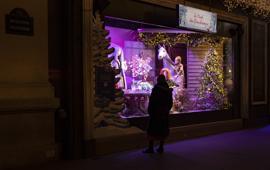 epa08836546 A pedestrian stops to look at the Christmas window display in a department store, in Paris, France, 22 November 2020. Department stores have unveiled Christmas window displays despite bein ...