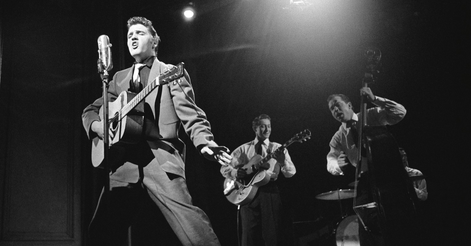 This March 17, 1956 photo provided by courtesy of Taschen shows, Elvis Presley, left, and band members, Scotty Moore, on guitar, Bill Black on bass, and DJ Fontana on drums, during a live performance  ...