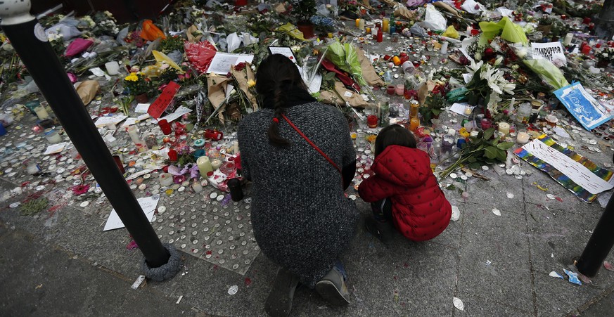 Eine Frau und ein Kind legen am Montag vor dem Restaurant Le Carillon in Paris Blumen für die Opfer nieder.