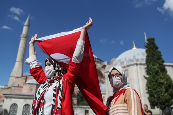 epa08538740 A woman holds a Turkish flag as they celebrate Turkey?s decision that the 1,500 year old Unesco World Heritage site Hagia Sophia can be converted into a mosque, in front of the Hagia Sophi ...