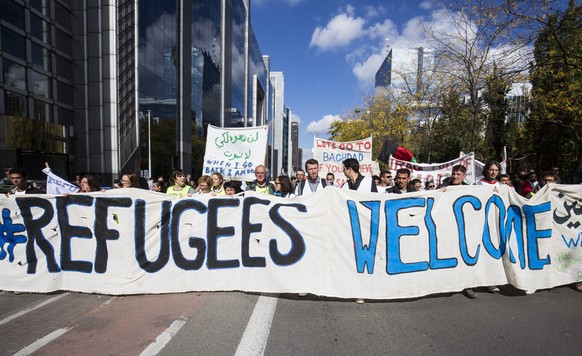 epa04952470 Demonstrators carry placards and banners as they attend a solidarity rally for migrants and refugees in the streets of Brussels, Belgium, 27 September 2015. Thousands of people earlier had ...