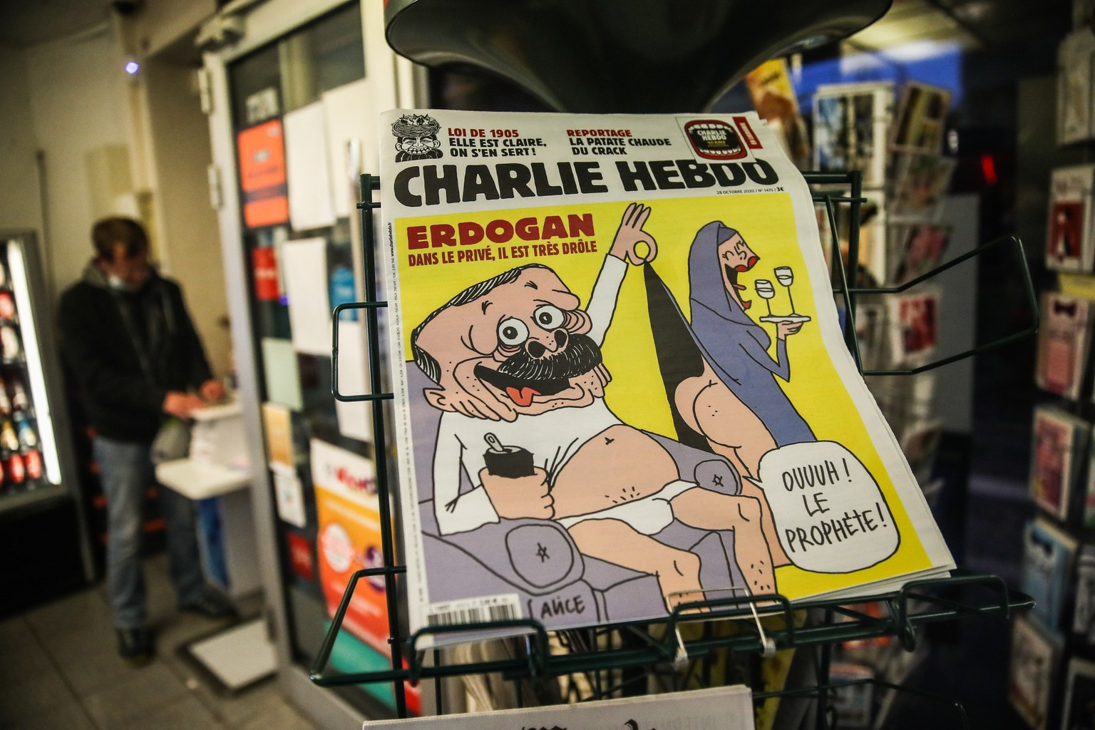 epa08781393 Copies of the new edition of the French satirical magazine Charlie Hebdo with a caricature of Turkish President Erdogan on its front page are on display at a newspaper kiosk in Paris, Fran ...