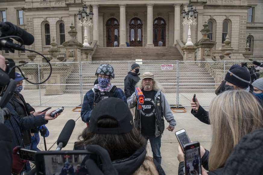 Members of the press interview one of the two Boogaloo Boys and Wayne Koper, 66, from Caro, while Koper holds a toy nerf gun at the State Capitol on Sunday, Jan. 17, 2021, in downtown Lansing, Mich. ( ...