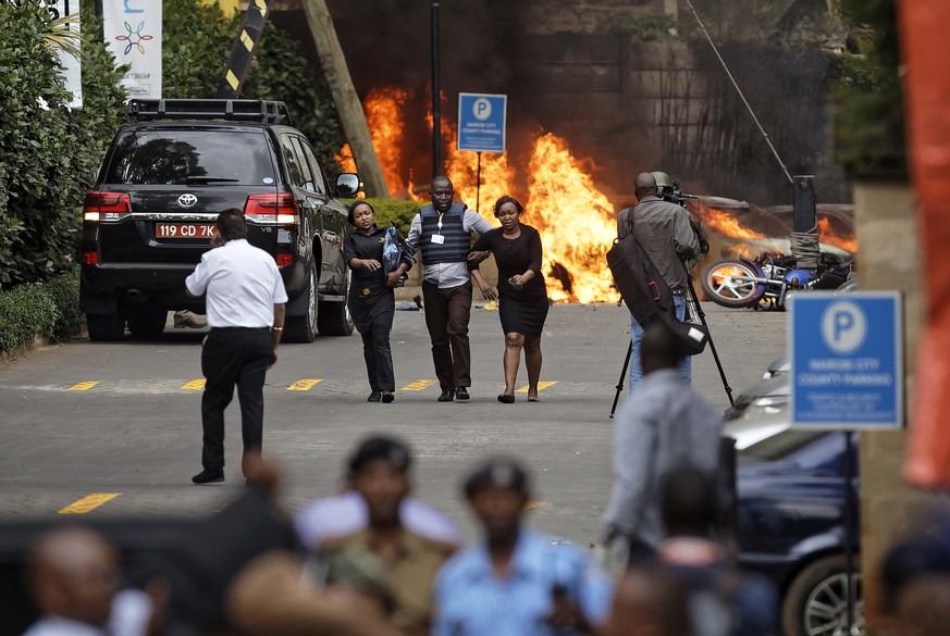 Security forces help civilians flee the scene as cars burn behind, at a hotel complex in Nairobi, Kenya Tuesday, Jan. 15, 2019. Terrorists attacked an upscale hotel complex in Kenya&#039;s capital Tue ...