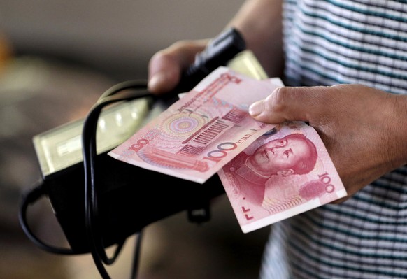 A customer holds a 100 Yuan note at a market in Beijing, August 12, 2015. REUTERS/Jason Lee/File Photo