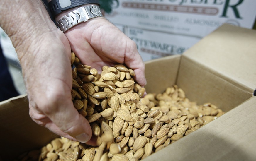 In this Tuesday, July 21, 2015 photo, Jim Jasper, owner of Stewart Jasper Orchards, displays a box of almonds that are ready for shipping at his processing plant in Newman, Calif. Like many Central Va ...