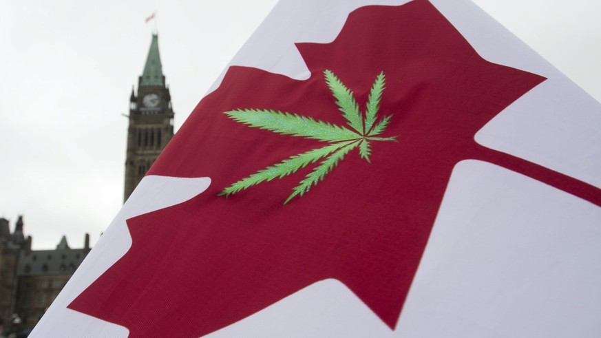 FILE - In this April 20, 2015 file photo, a Canadian flag with a cannabis leaf flies on Parliament Hill during a 4/20 event in Ottawa, Ontario. Another big first for the marijuana industry is in the b ...