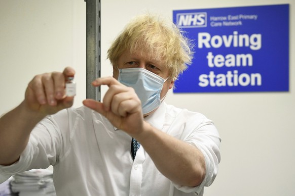 Britain&#039;s Prime Minister Boris Johnson holds a vial of the Oxford Astrazeneca coronavirus vaccine, during a visit to Barnet FC&#039;s ground at the Hive, which is being used as a coronavirus vacc ...