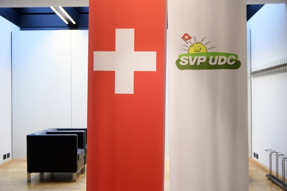 Die Schweizer Flagge und das Logo der SVP fotografiert an der Pressekonferenz ueber die Beschluesse des SVP Parteileitungsausschusses, am Dienstag, 6. Maerz 2018 im Bundeshaus in Bern. (KEYSTONE/Antho ...