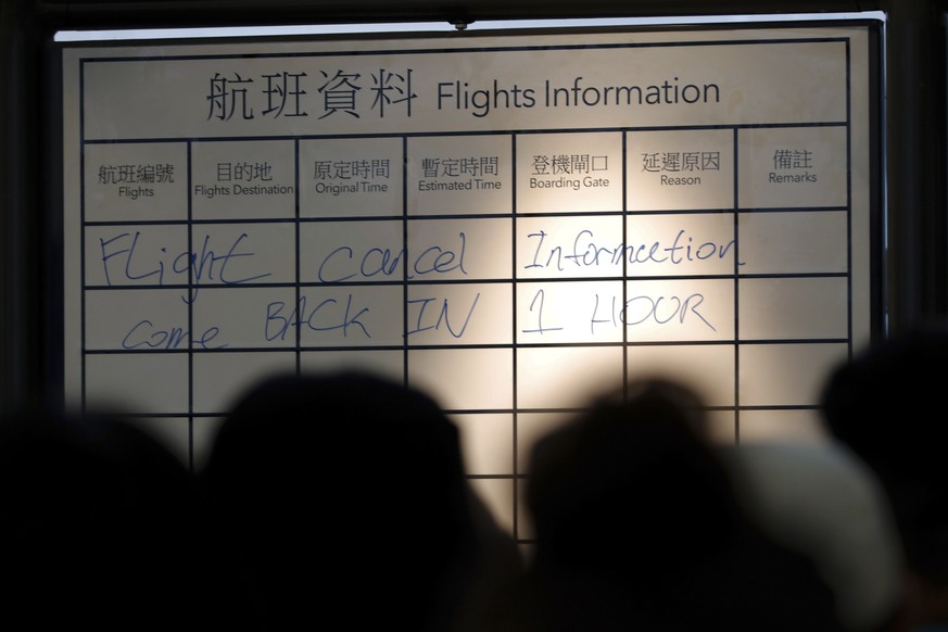 Travelers gather near a flights information board at the Hong Kong International airport, Monday, Aug. 12, 2019. One of the world&#039;s busiest airports canceled all flights after thousands of Hong K ...