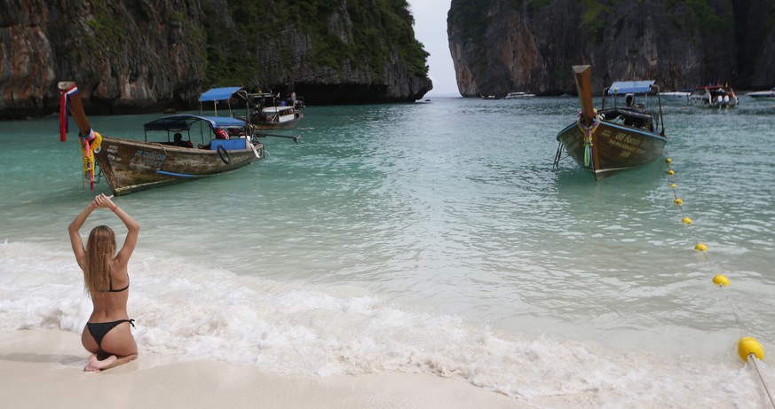 A tourist poses for a photo on Maya Bay, Phi Phi Leh island in Krabi province, Thailand, Thursday, May 31, 2018. The popular tourist destination of Maya Bay in the Andaman Sea will close to tourists f ...