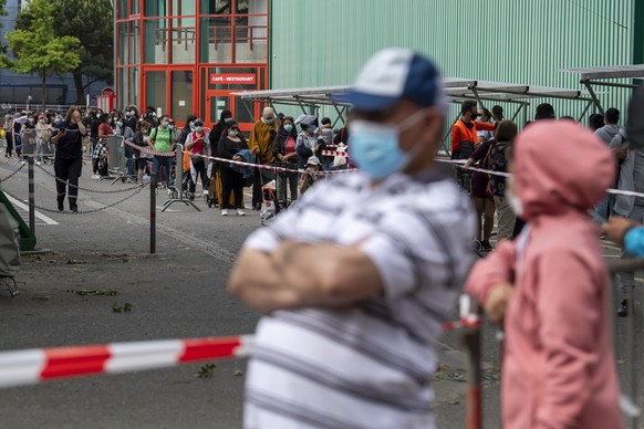 epa08439100 People queue to receive bags with free food and essential products received from donations at the ice stadium Les Vernets, in Geneva, Switzerland, 23 May 2020. The ongoing coronavirus COVI ...