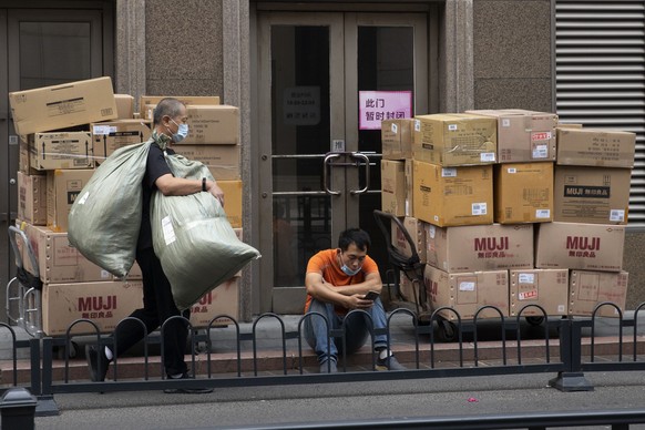 Delivery workers wait with their goods outside a mall in Beijing on Wednesday, Aug. 26, 2020. U.S. and Chinese trade envoys discussed strengthening coordination of their countries&#039; economic polic ...