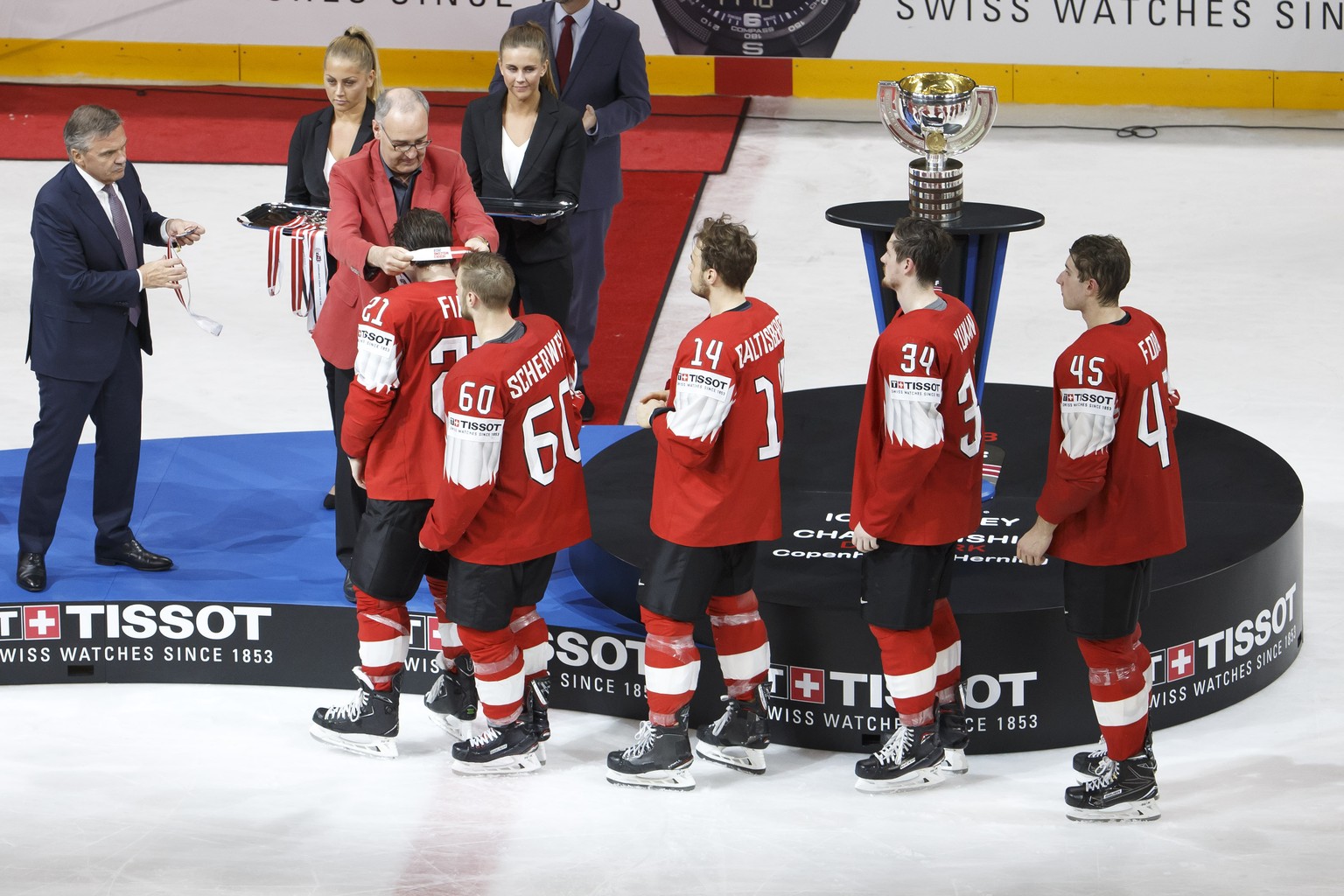 Swiss Defense and Sport Minister Guy Parmelin, 2nd left, next to Rene Fasel, left, President of IIHF, gives the silver medal to Switzerland&#039;s forward Kevin Fiala past #21 teammates forward Trista ...