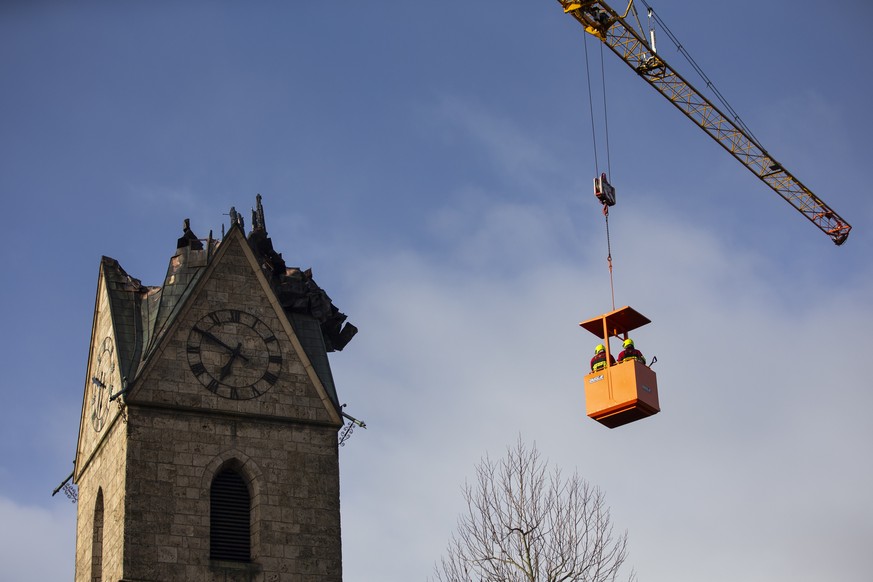 Feuerwehrleute schauen sich die abgebrannte Spitze des Kirchturms der reformierten Kirche von Herzogenbuchsee BE aus einem Kran an, am Mittwoch, 25. Dezember 2019. Das Feuer im Turm der reformierten K ...