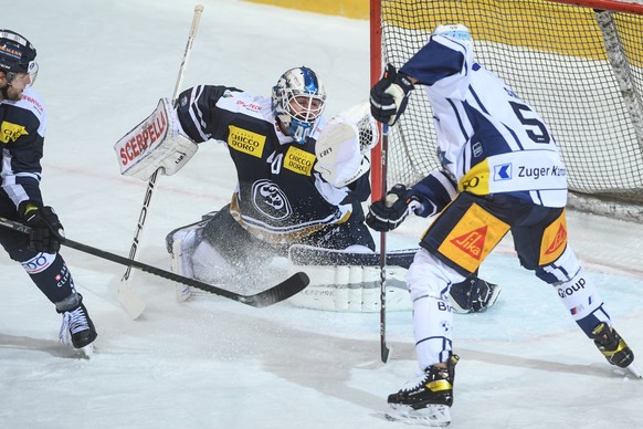 Ambri&#039;s goalkeeper Damiano Ciaccio, left, fights for the puck with Zug&#039;s player Dario Simion, right, during the preliminary round game of National League Swiss Championship 2020/21 between H ...