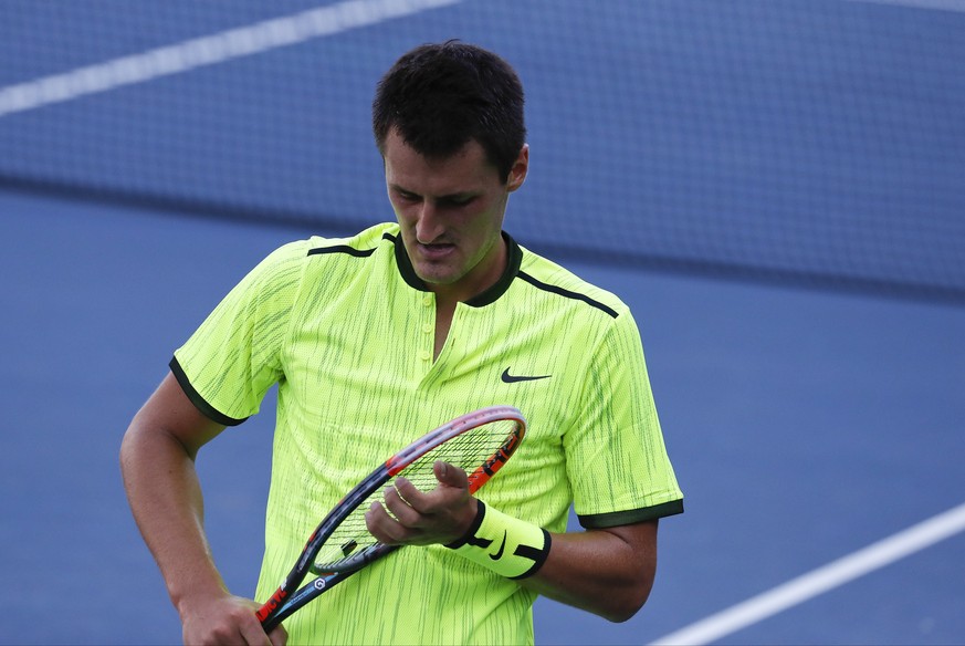 Bernard Tomic, of Australia, adjusts the strings on his racket between serves from Damir Dzumhur, of Bosnia and Herzegovina, during the first round of the U.S. Open tennis tournament, Tuesday, Aug. 30 ...