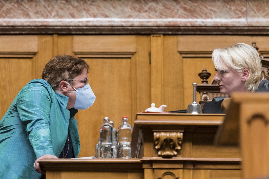 Magdalena Martullo-Blocher, SVP-GR, links, eine Atemschutzmaske tragend, diskutiert mit der Ratspraesidentin Isabelle Moret, FDP-VD, am ersten Tag der Fruehlingssession der Eidgenoessischen Raete, am  ...