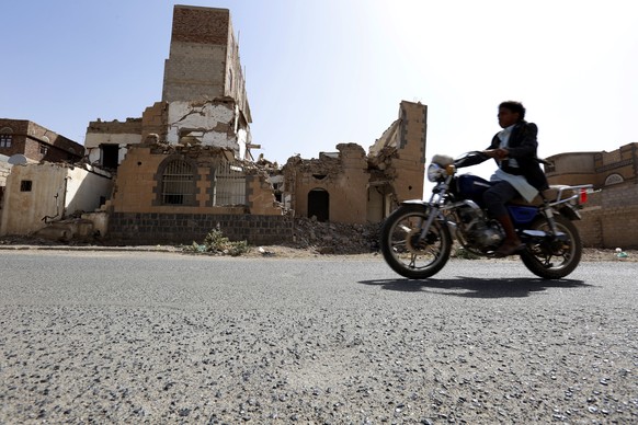 epa07343436 A Yemeni rides a motorbike past a destroyed building allegedly targeted by a previous Saudi-led airstrike, in Sana&#039;a, Yemen, 04 February 2019. According to reports, representatives of ...