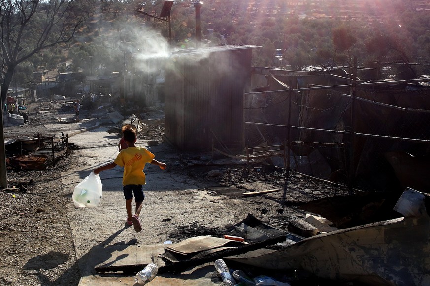 epa08656982 A child walks among debris in the Moria refugees camp on the island of Lesbos, Greece, 09 September 2020. According to reports, a fire broke out at Moria Camp early on 09 September, after  ...