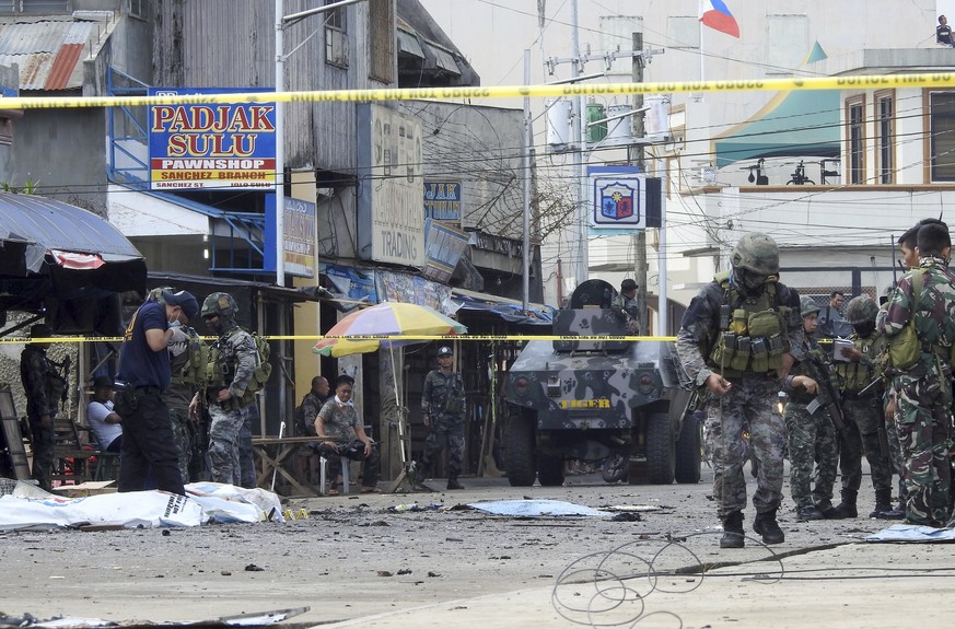 Police investigators and soldiers attend the scene after two bombs exploded outside a Roman Catholic cathedral in Jolo, the capital of Sulu province in southern Philippines, Sunday, Jan. 27, 2019. Two ...