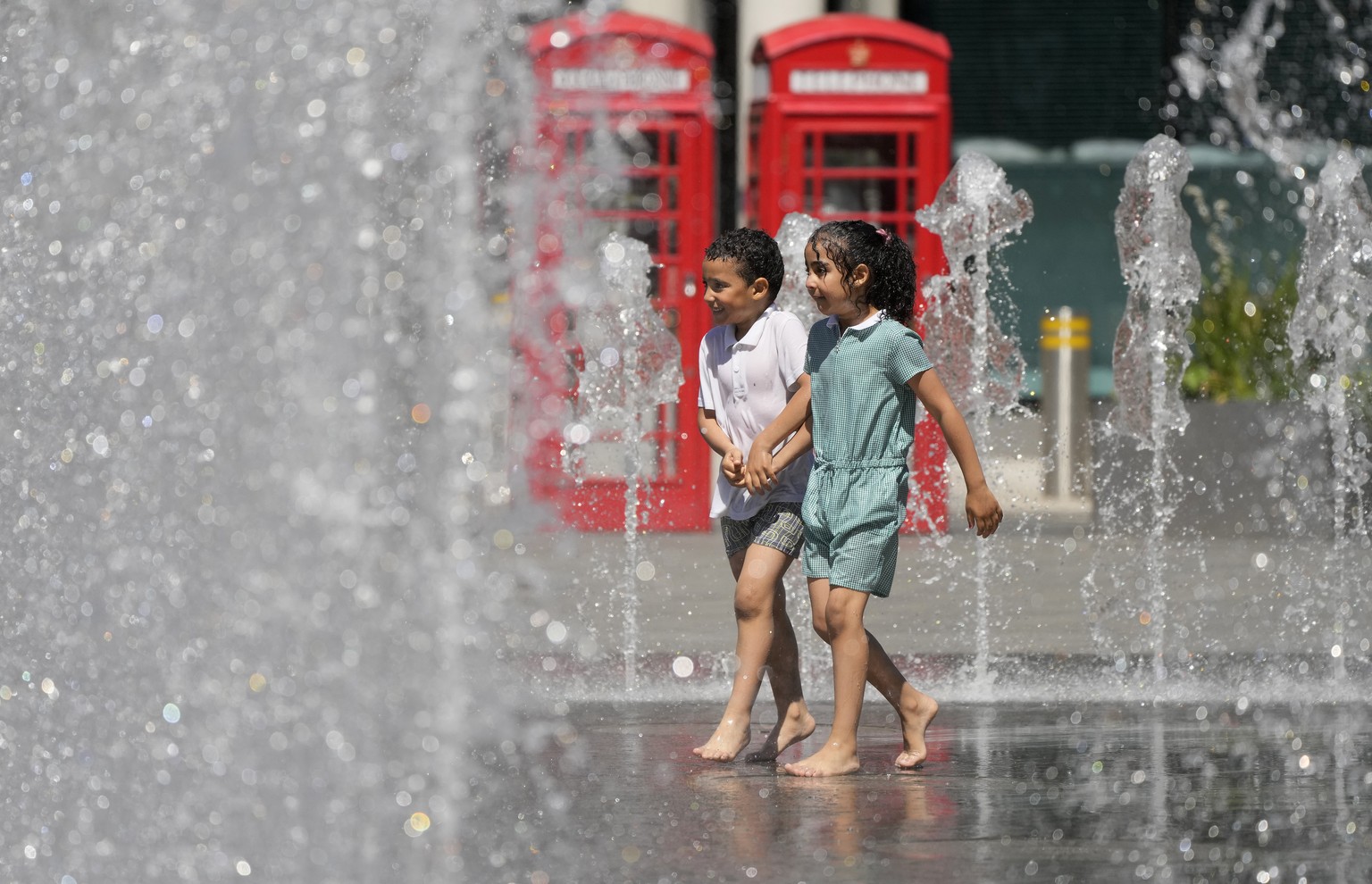 Five year old twins Amir and Sophia play in a fountain at wembley stadium to refresh from the sunny and hot weather before the Euro 2020 soccer championship in London, Wednesday, June 9, 2021. Euro 20 ...