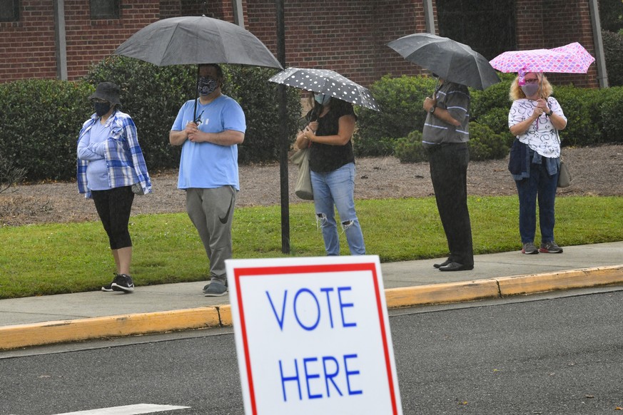 epa08738737 Voters wait in the rain in a line to vote that has an estimated 3-hour as the first day of early voting is underway at the George Pierce Park in Suwanee, Georgia, USA, 12 October 2020. EPA ...