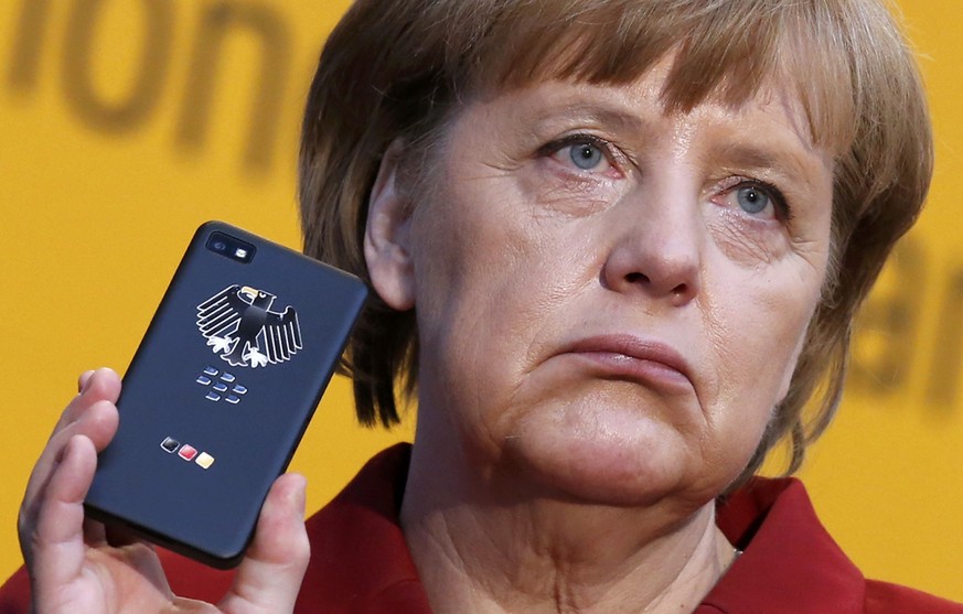 File photo of German Chancellor Angela Merkel holding a BlackBerry Z10 smartphone featuring high security Secusite software, used for governmental communication, at the booth of Secusmart during her o ...