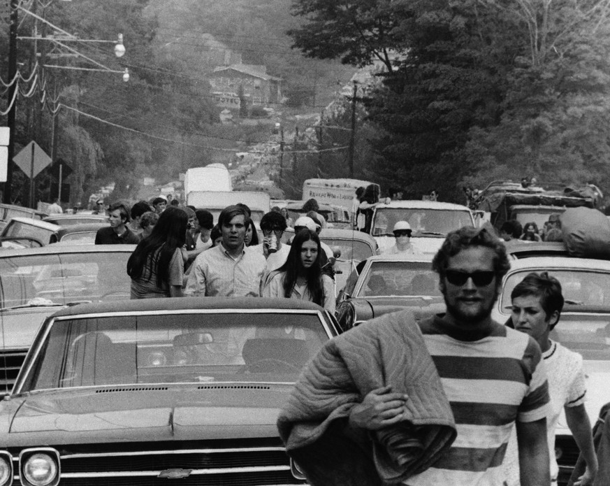 FILE -This Aug. 15, 1969 file photo shows people abandoning their trucks, cars and buses, backed up for 10 miles, as some 200,000 festival goers try to reach the Woodstock Music and Art Festival in Be ...