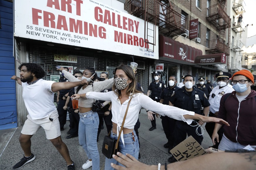 epa08456964 Peaceful protesters lock arms and surround police to protect them from thown bottles, during protest over the death of George Floyd, who died in police custody in Greenwich Village, New Yo ...