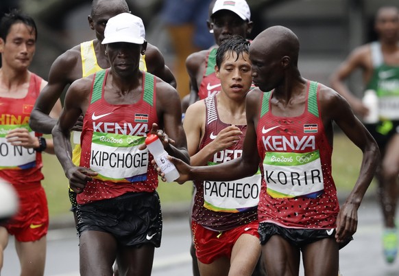 Wesley Korir, of Kenya, right, hands a bottle of water to eventual winner Eliud Kipchoge, also of Kenya, in the men&#039;s marathon at the 2016 Summer Olympics in Rio de Janeiro, Brazil, Sunday, Aug.  ...