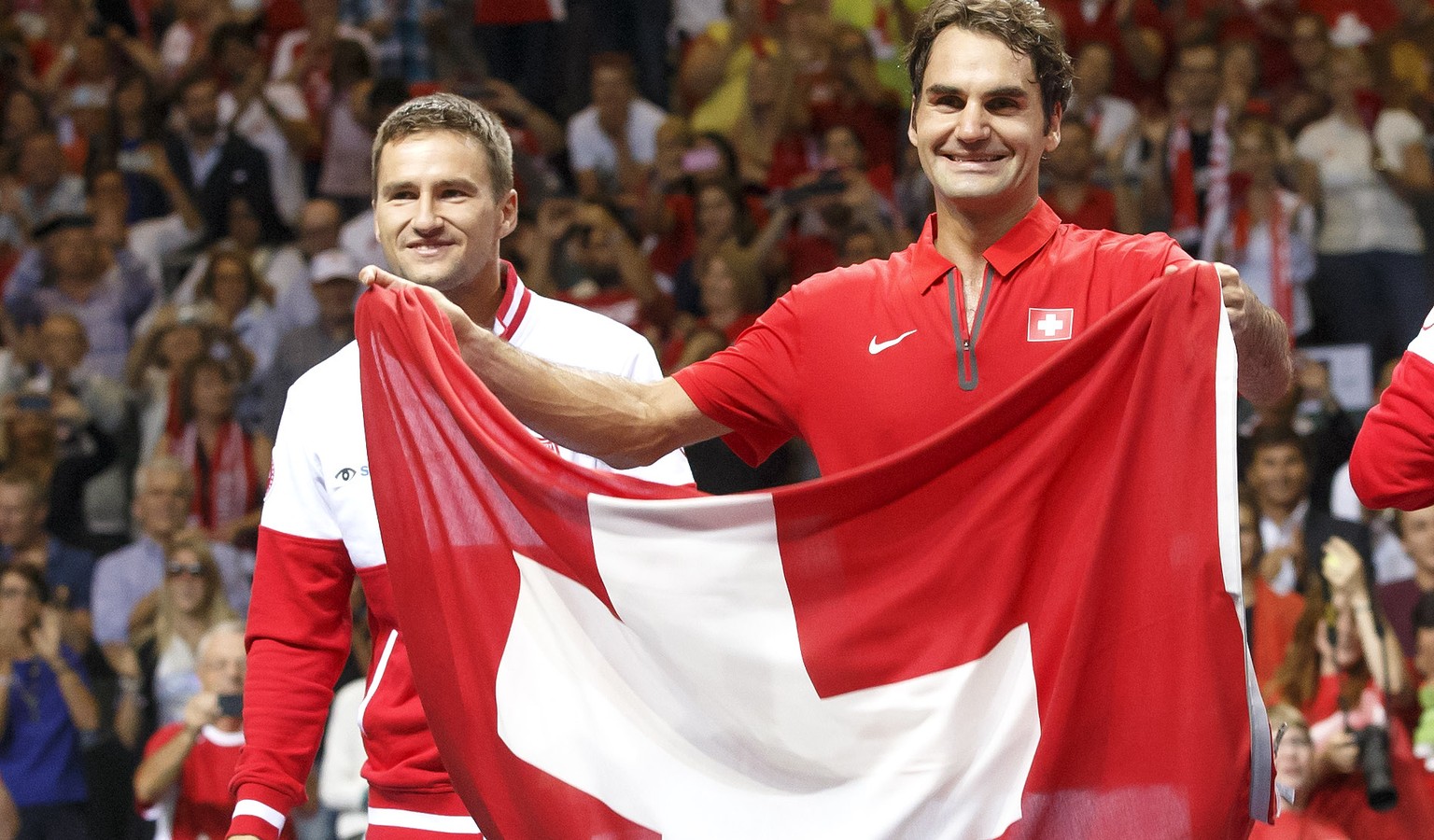 Roger Federer jubelt mit Schweizer Fahne und Marco Chiudinelli.