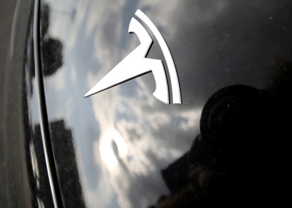 In this July 8, 2018, photo, clouds are reflected above the company logo on the hood of a 2018 Model 3 sedan on display outside a Tesla showroom in Littleton, Colo. Board members at Tesla are evaluati ...