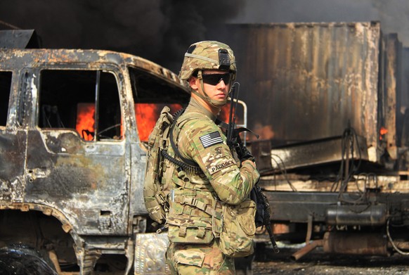 epa04266069 A US soldier inspects the scene of suicide bomb attacks that targeted NATO logistic compound, in the Torkham area of the Nangarhar province, a crossing point on the border between Pakistan ...