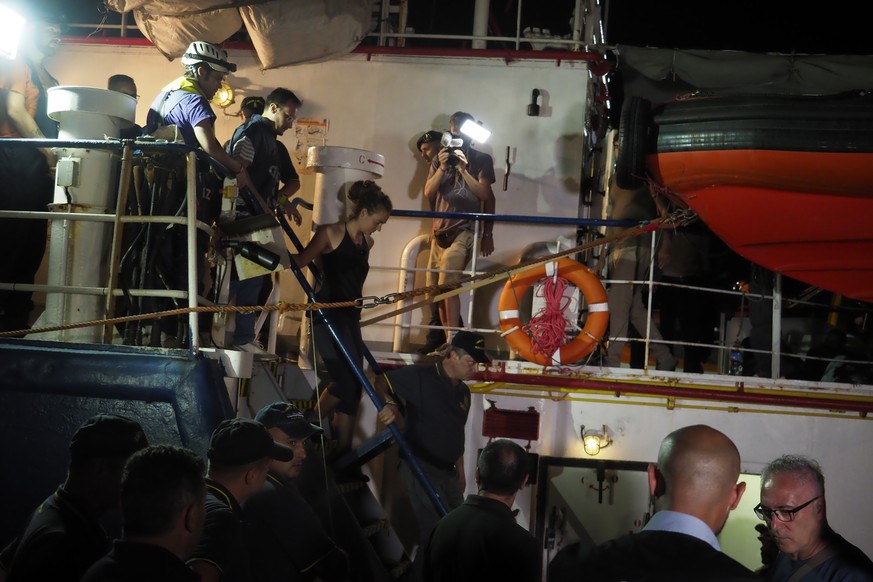epa07682745 A handout photo made available by Sea-Watch shows Sea Watch 3 captain Carola Rackete (C) being arrested after entering the port of Lampedusa and ramming a patrol boat, in Lampedusa, Italy, ...
