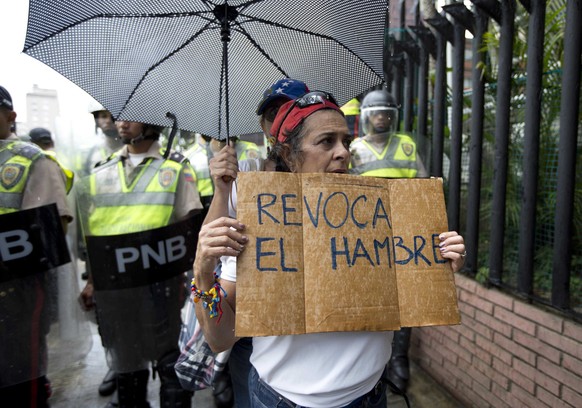 A woman holds a sign with a message that in reads in Spanish; &quot;Revoke hunger&quot; during a protest march in Caracas, Venezuela, Wednesday, July 27, 2016. Venezuela&#039;s opposition marched Wedn ...
