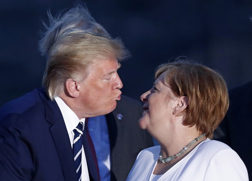 epaselect epa07793896 US President Donald J. Trump (L) kisses German Chancellor Angela Merkel (R) as they pose for the family photo during the G7 summit at Casino in Biarritz, France, 25 August 2019.  ...