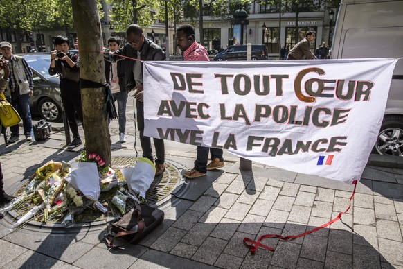 epa05919233 People pay tribute, in front of a banner reading, &#039;With all my heart with the police, Long live France,&#039; to the French policeman killed at the Champs Elysee avenue in Paris, 21 A ...