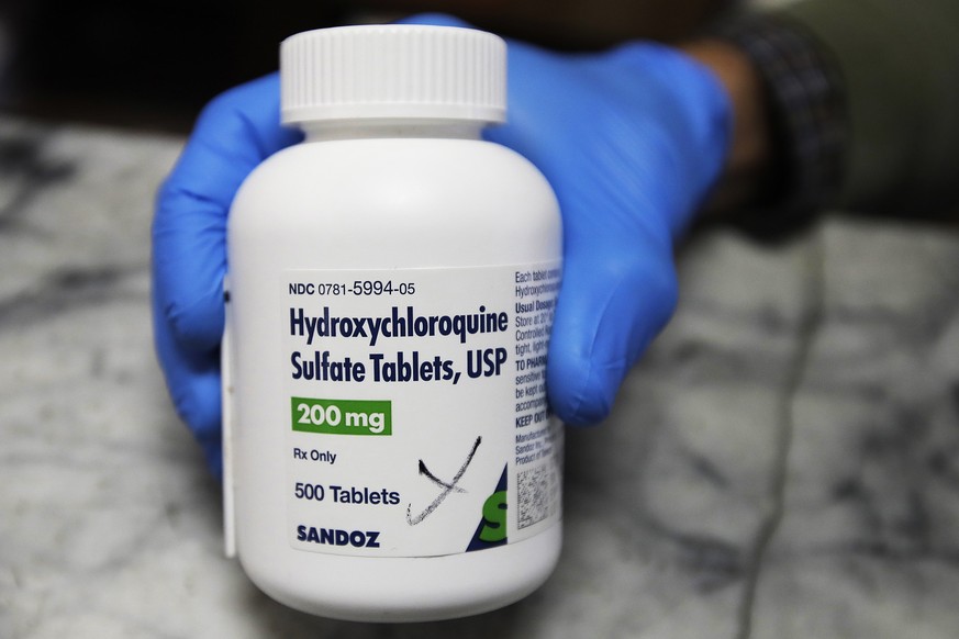 FILE - In this April 6, 2020 file photo, a pharmacist holds a bottle of the drug hydroxychloroquine in Oakland, Calif. Results published Wednesday, June 3, 2020, by the New England Journal of Medicine ...