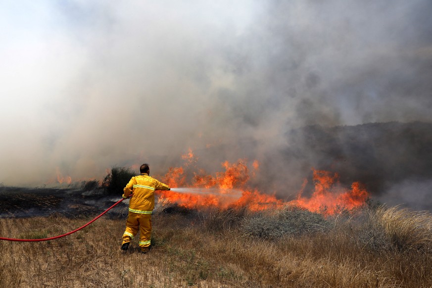 epa06786262 Israeli firefighters try to extinguish a fire that ignited at a field as a result of a Molotov cocktail kite that was sent from Gaza Strip few kilometers from the border with Gaza near Kib ...
